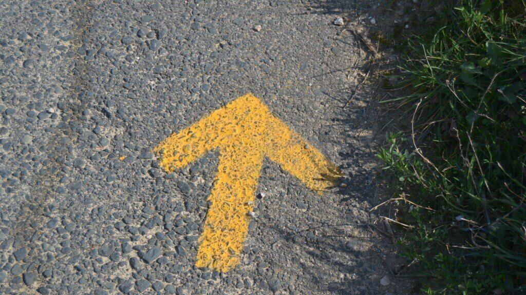Una flecha amarilla del Camino de Santiago pintada en una carretera