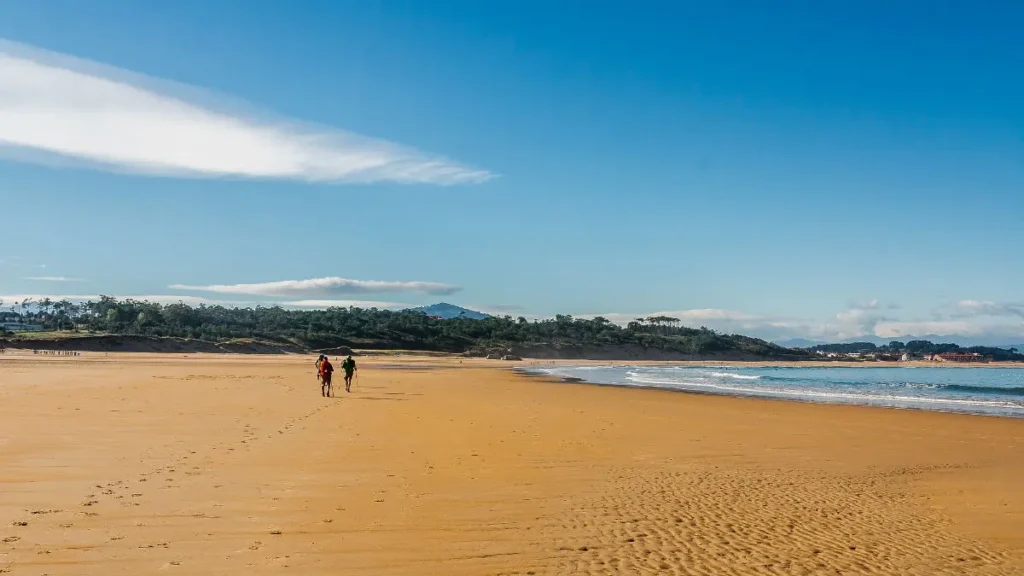 Peregrinos caminando por una playa de Cantabria - Camino del Norte :: Guía del Camino de Santiago
