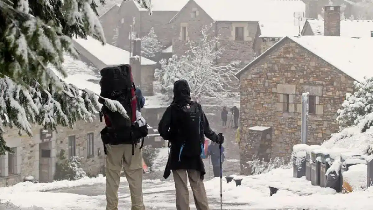 Dos peregrinos haciendo el Camino de Santiago en invierno con nieve