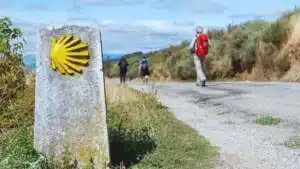 Un peregrino del Camino junto a un mojón de señalización