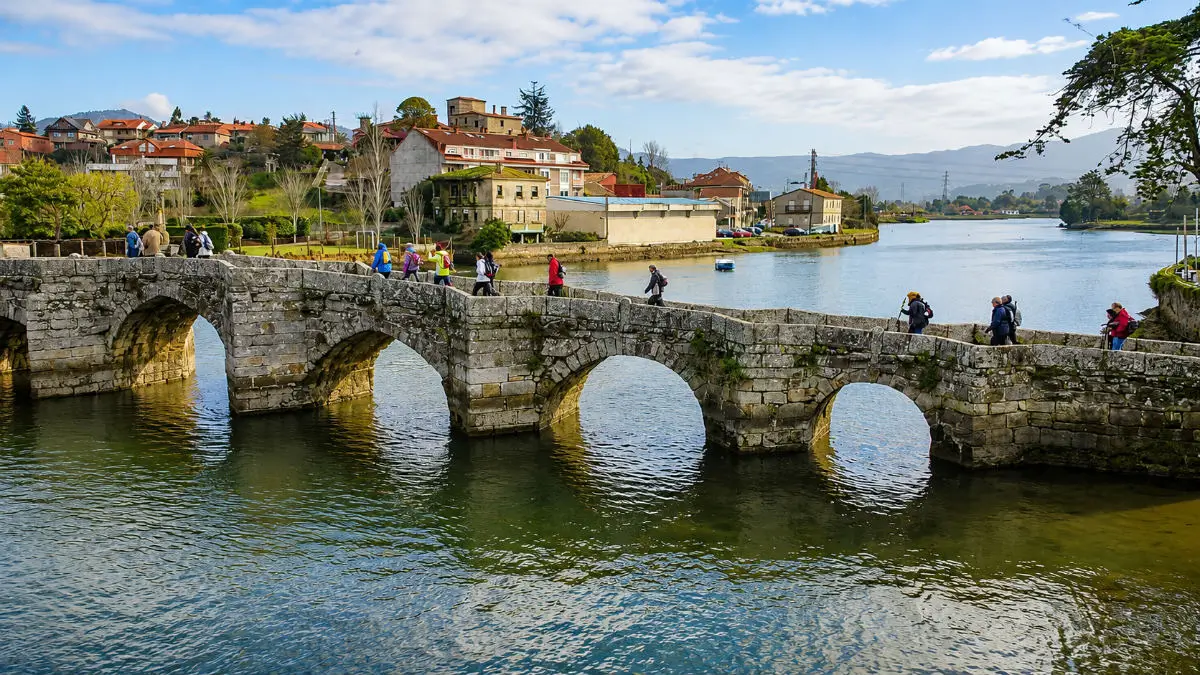 Peregrinos cruzando el puente de A Ramallosa en el Camino Portugués por la Costa
